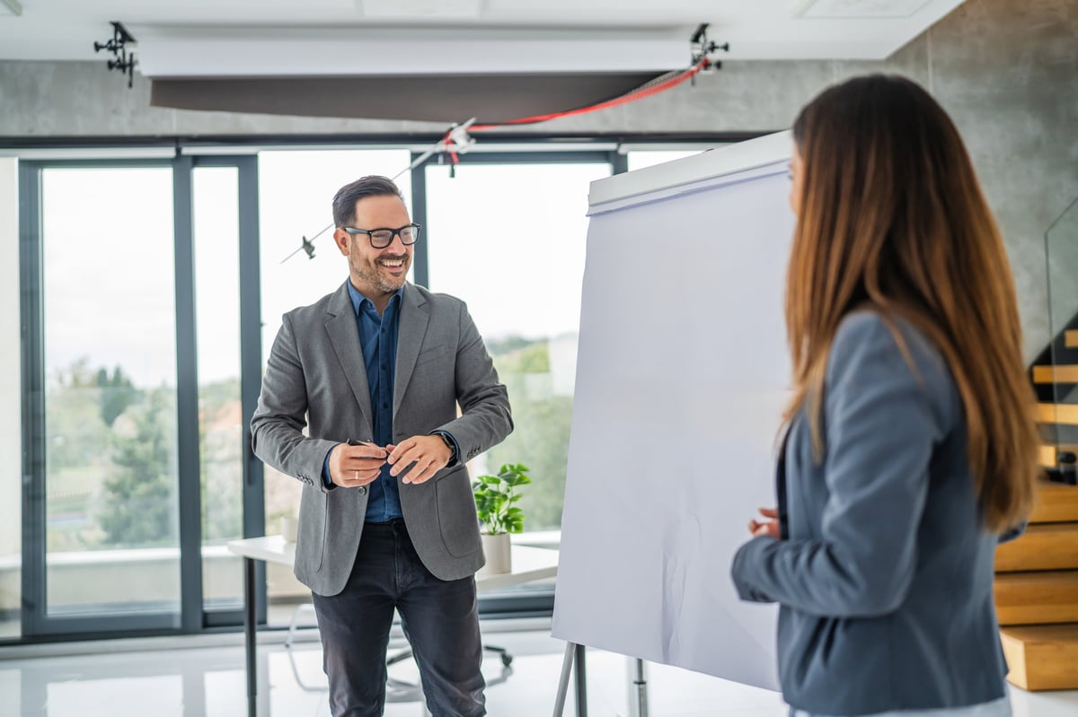 Dos profesionales colaborando frente a un rotafolio durante una reunión, intercambiando ideas en un entorno de oficina moderno